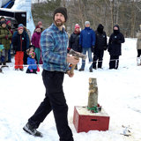 Image shows a man preparing to throw an axe. 