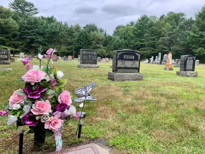 Image shows a cemetery with floral arrangement in the foreground. 