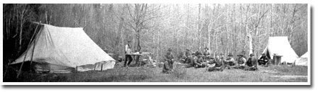 Image shows a lumber camp with white tents.