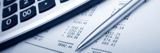 Image shows a calculator, pen and financial documents. 