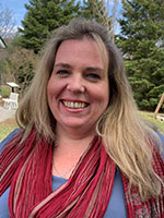 Image shows headshot of a woman against a natural backdrop.