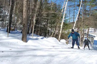 Image shows couple skiing on a snowy trail.