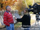 Image shows a man being interviewed by a television reporter. 