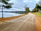 Image shows a road running along the shore of a lake. 