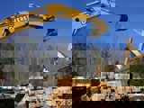 Image shows a backhoe and pile of lumber. 