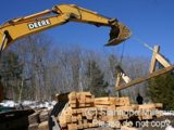 Image shows a backhoe and pile of lumber. 