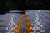 Image shows yellow centre lines on a paved road. 
