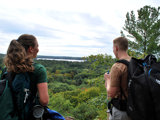 Image shows a man and woman overlooking a forested vista. 