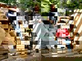 Image shows a group of people posing with the partially constructed frame of the new log chute. 