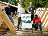Image shows a group of people posing with the partially constructed frame of the new log chute. 