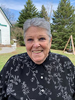 Image shows the headshot of a woman against a natural backdrop.