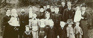 Image shows a black and white photo of a family dressed in old-fashioned clothing. 