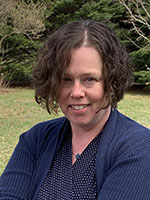 Image shows headshot of a woman against a natural backdrop.