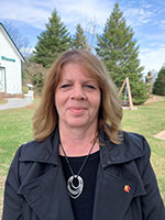 Image shows headshot of a woman against a natural backdrop.