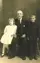 Image shows what appears to be a family portrait with a seated man between two standing children. 