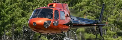 Image shows a red and black helicopter in flight. 